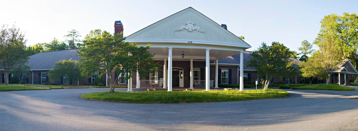 A classic building with white columns and a porch at the entrance.