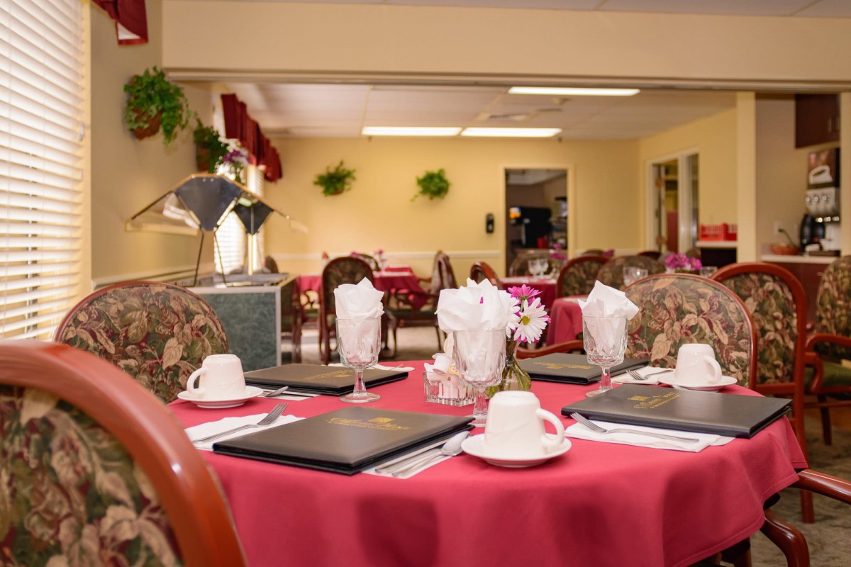 An elegantly set dining table in a restaurant with red tablecloths and tea cups.