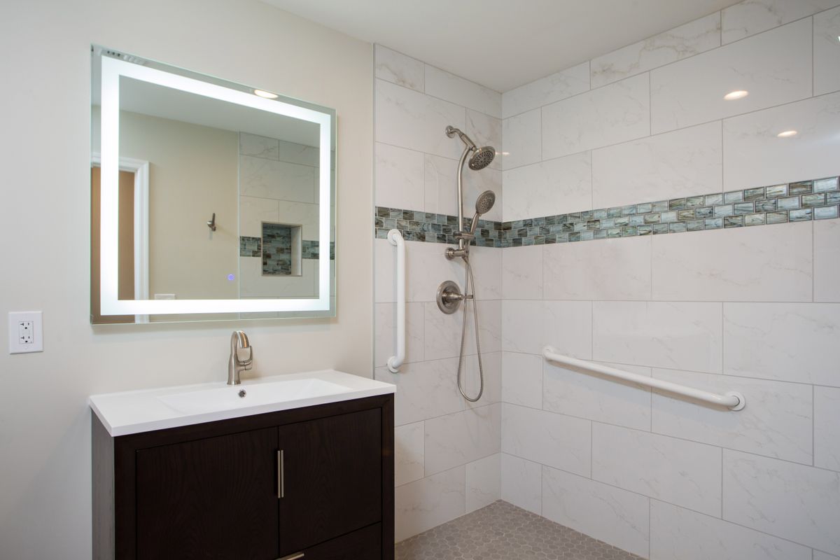 A modern bathroom with a walk-in shower and illuminated vanity mirror.