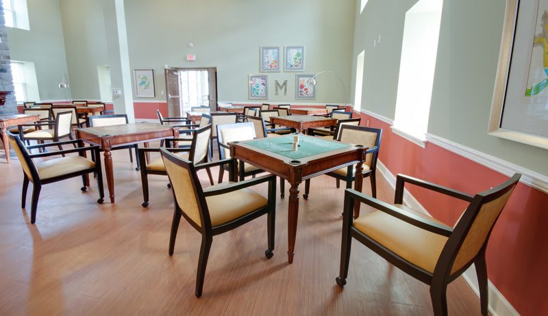 An empty game room with several tables and chairs arranged for leisure activities.
