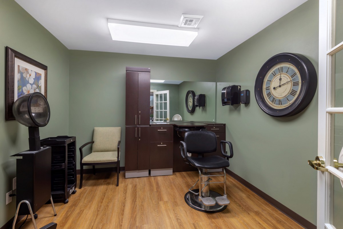 A modern barber or salon interior featuring a styling chair, mirror, and clock.