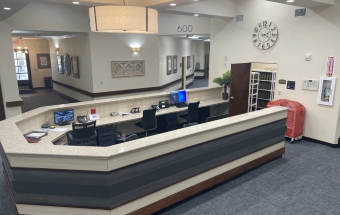 A modern reception area with a desk, computers, and a wall clock.
