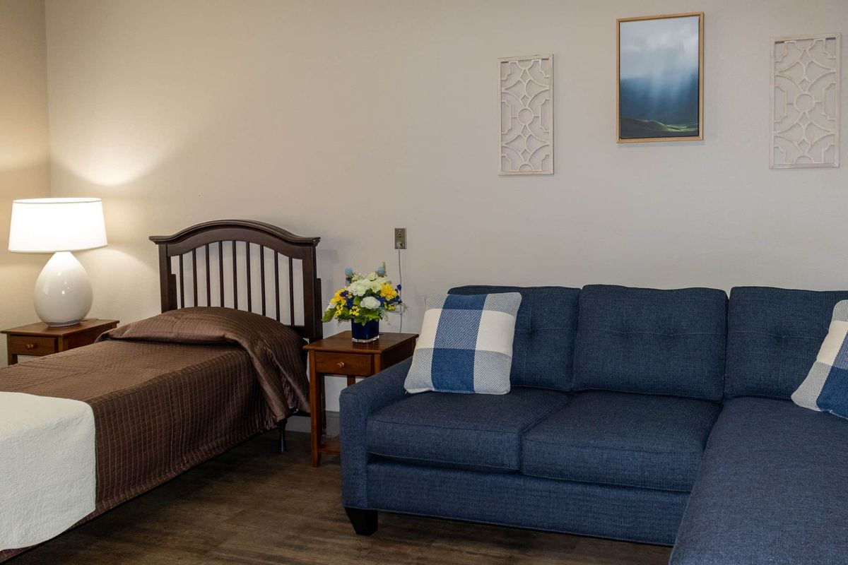 A cozy bedroom with a wooden bed, blue sofa, and decorative elements.