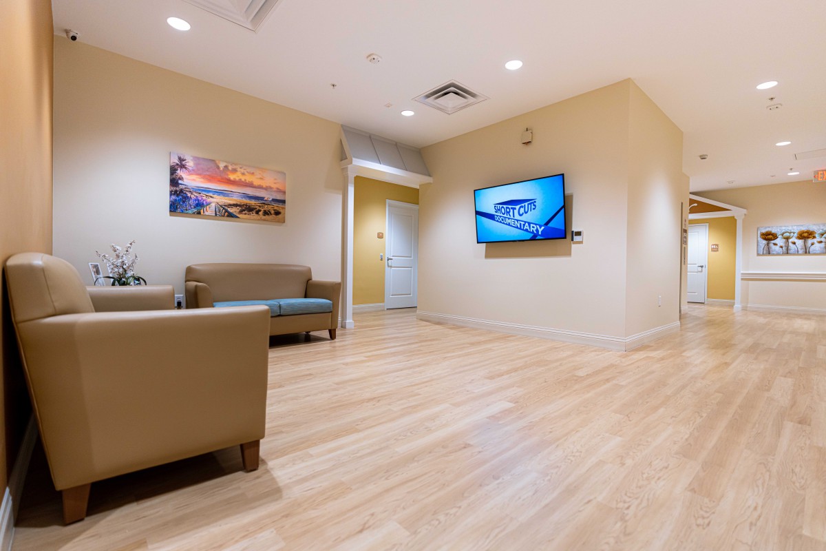 A modern waiting room with comfortable seating and a television display.