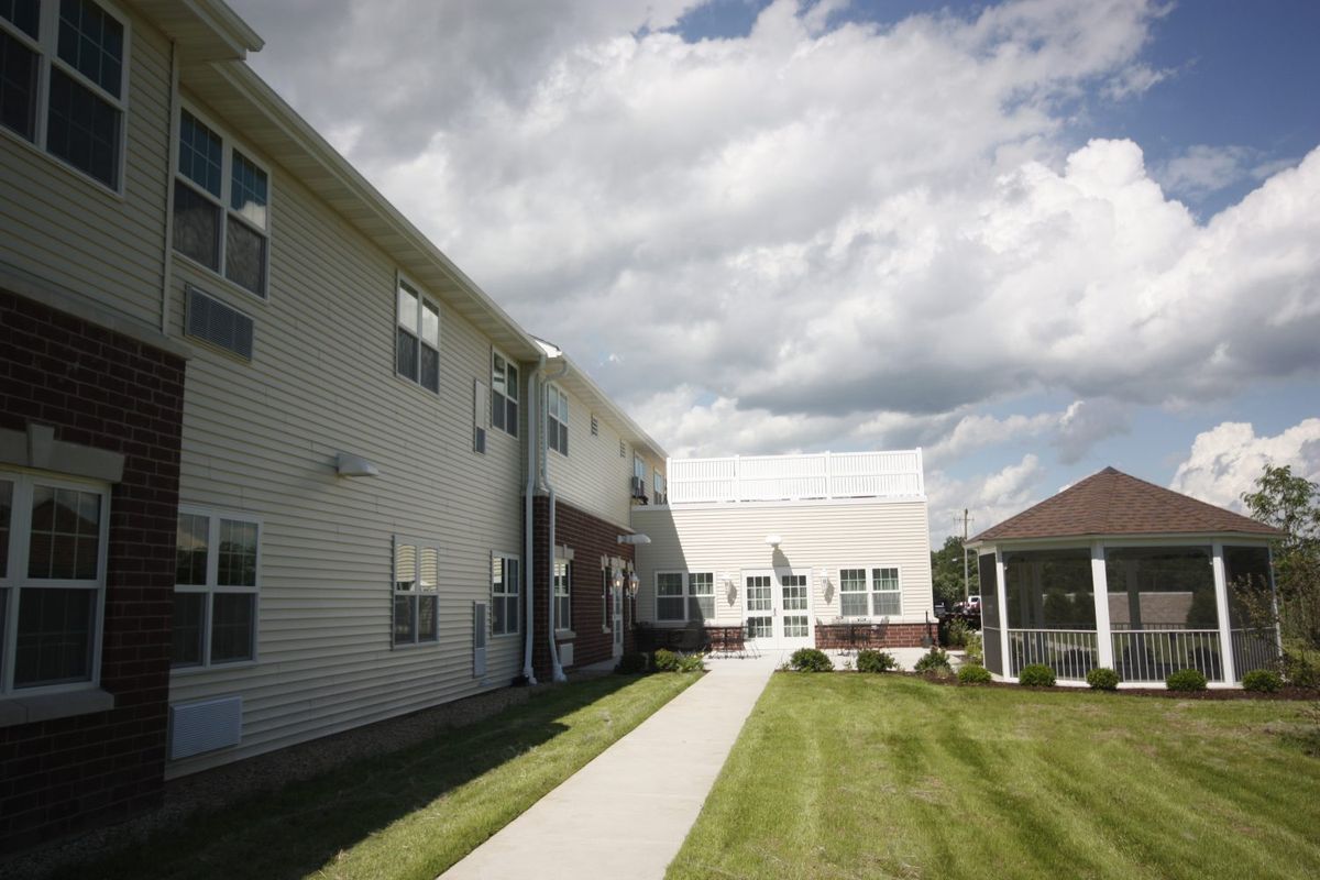 A two-story building with a grassy lawn and a pathway under a cloudy sky.