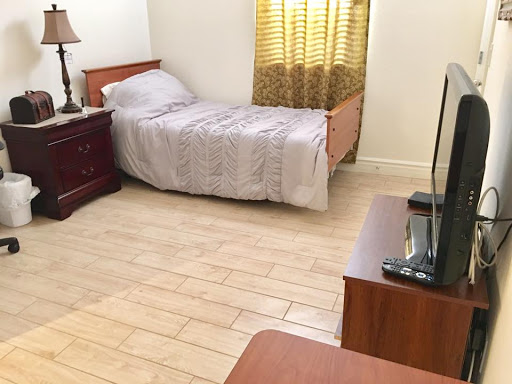 A cozy bedroom featuring a single bed, wooden furniture, and warm curtains.
