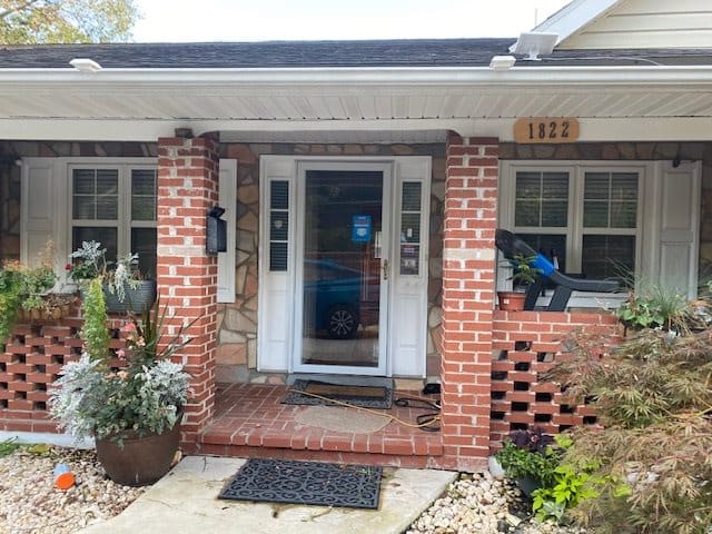 A cozy home entrance with brick walls and plants.