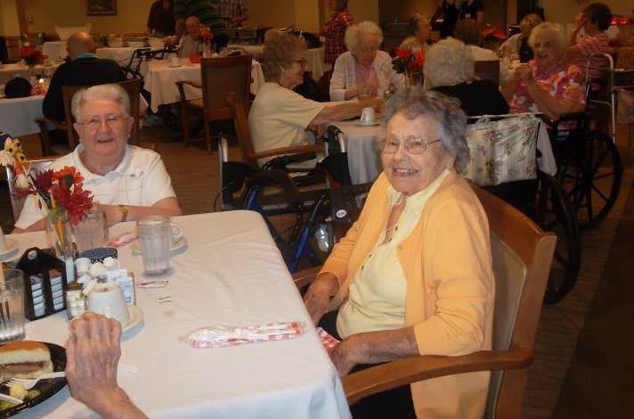 A group of elderly people enjoying a meal together in a dining setting.
