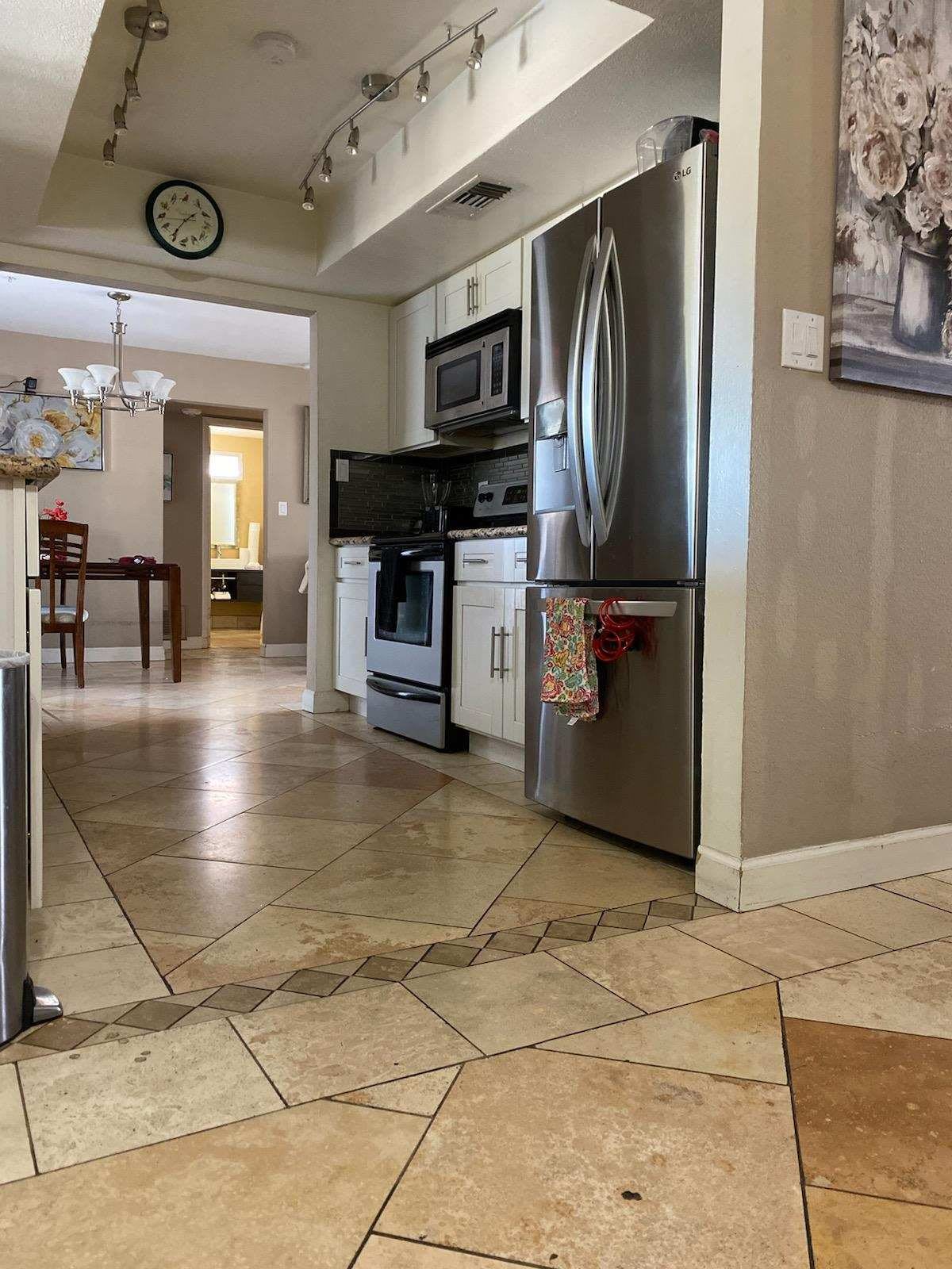 A modern kitchen with tiled flooring, stainless steel appliances, and neutral interior decor.