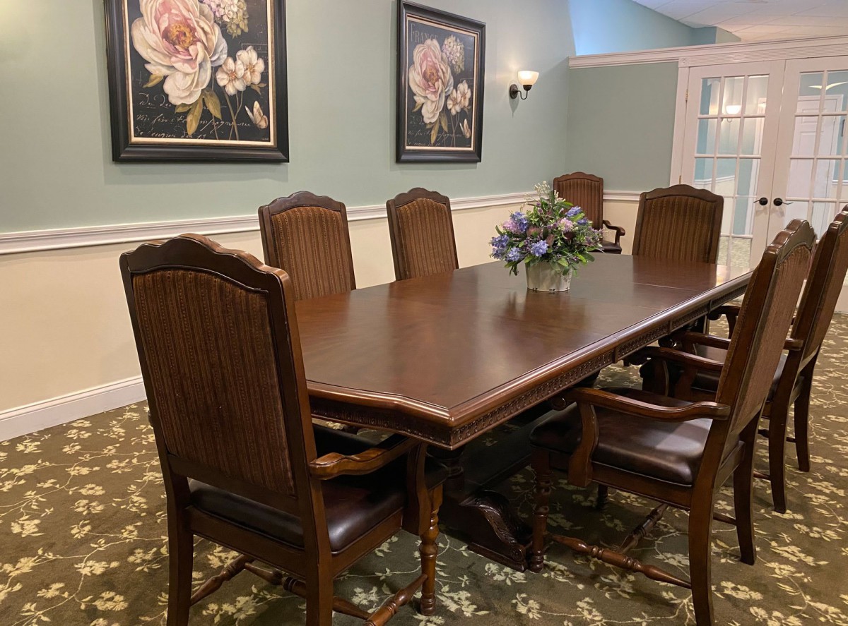 A dining room with a wooden table and chairs, adorned with floral artwork on the walls.