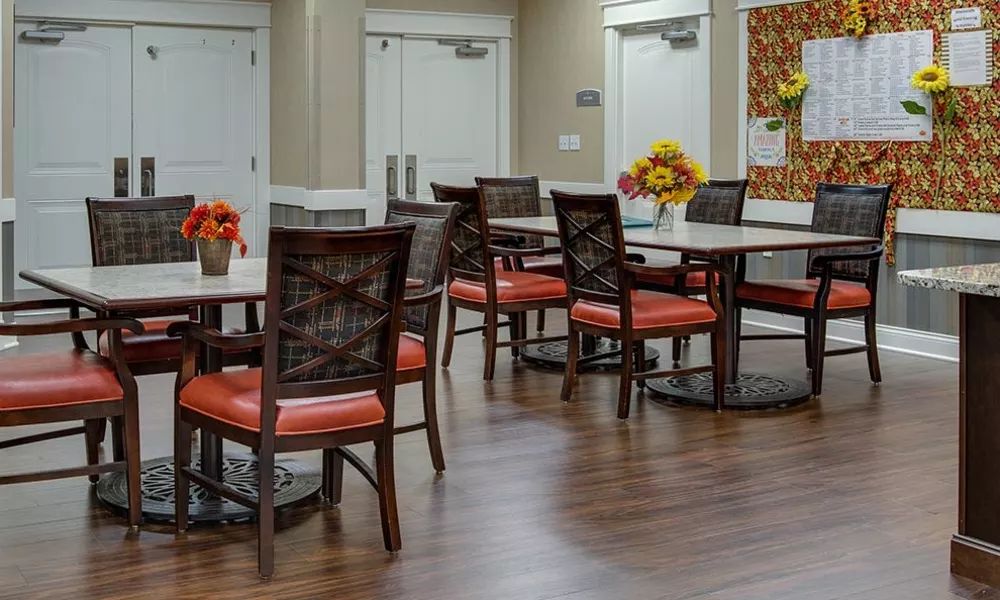 A dining area with arranged tables and chairs, decorated with floral centerpieces.