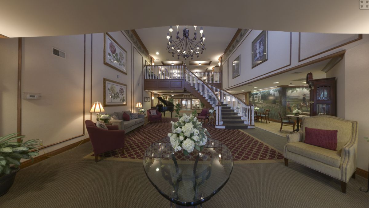 A luxurious hotel lobby featuring a grand staircase, elegant chandelier, and plush seating arrangements.