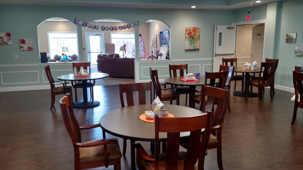 A cozy dining area with neatly arranged tables and chairs, featuring warm decor.