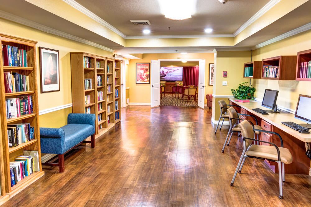 A cozy library room with wooden floors, bookshelves, and seating areas.