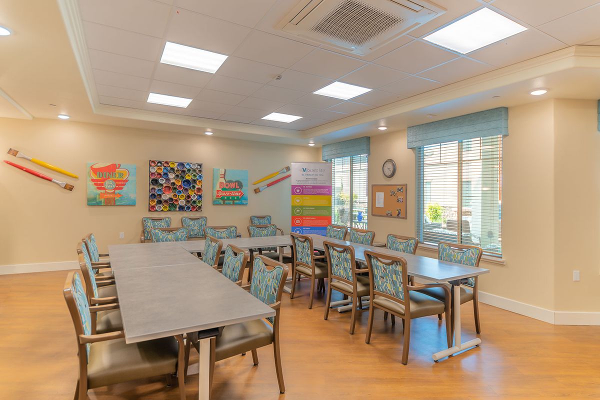 A well-lit room with multiple tables and chairs, adorned with colorful artwork on the walls.