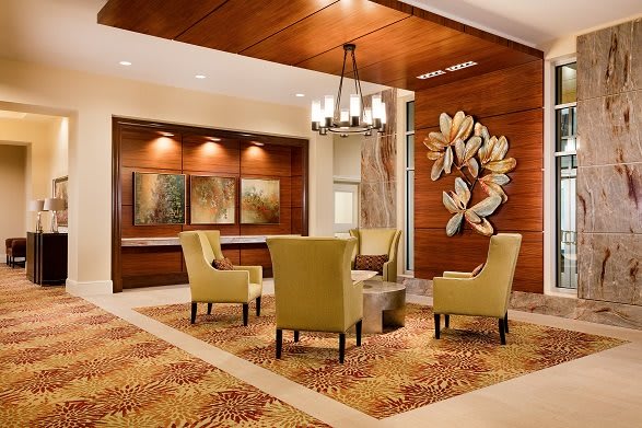 A modern lobby with comfortable seating, decorative artwork, and a stylish chandelier.