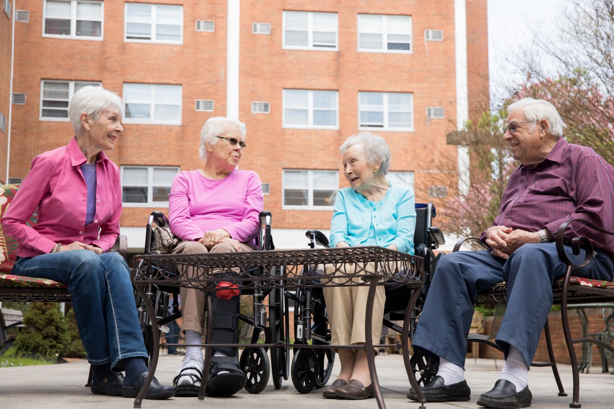 A group of seniors sitting together outside, engaging in conversation.
