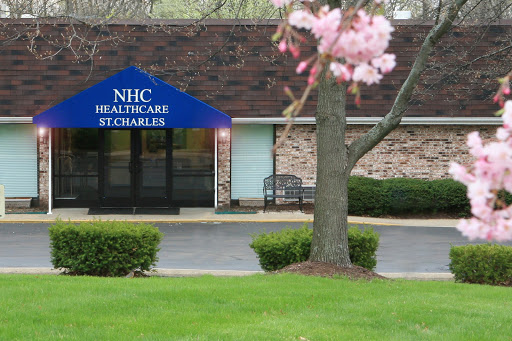 The entrance of NHC Healthcare in St. Charles, surrounded by blooming trees and a well-kept lawn.