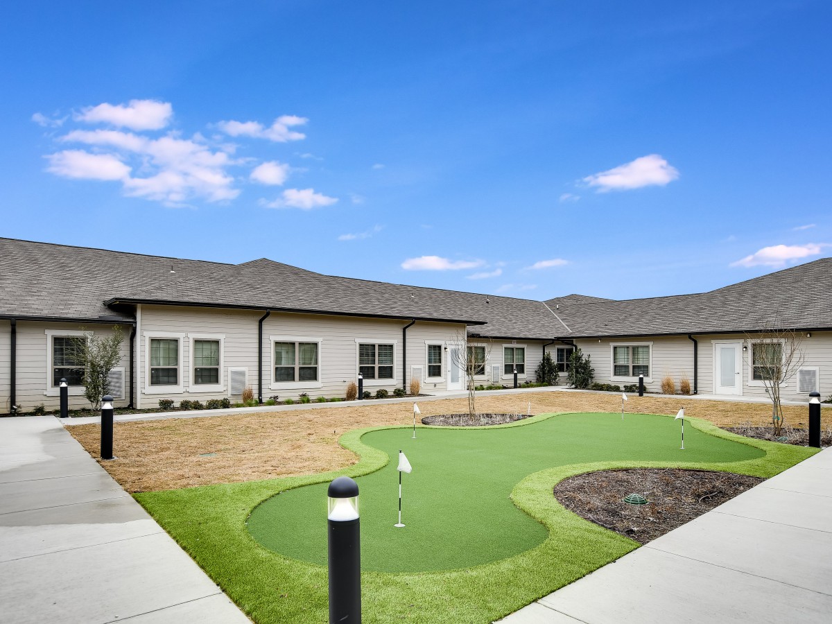 A modern building with a small putting green under a clear blue sky.
