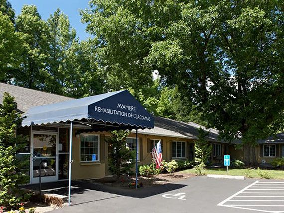 A sunny view of a small building with an awning labeled 'Office' surrounded by trees and a parking lot.