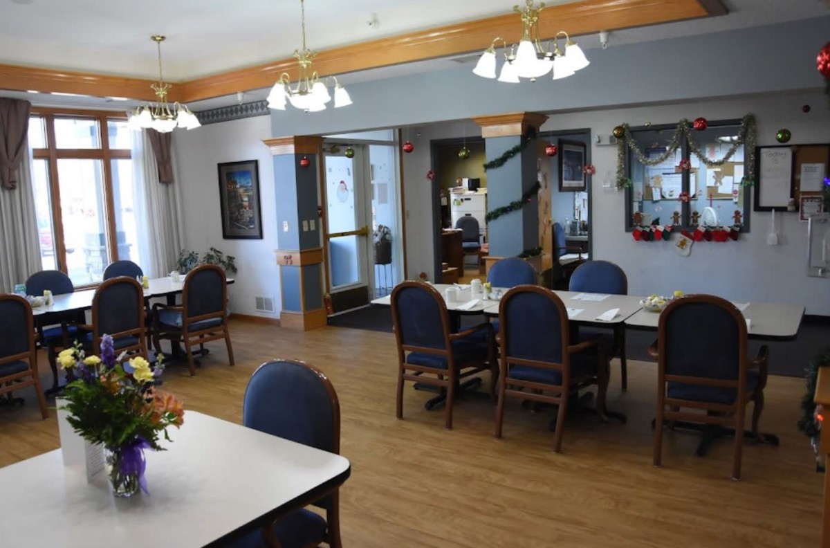 A cozy dining area with neatly arranged tables and chairs, illuminated by hanging lights.