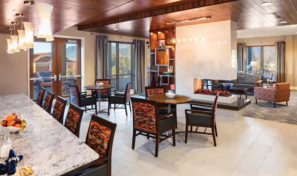 A modern dining area with a cozy fireplace and wooden furniture.
