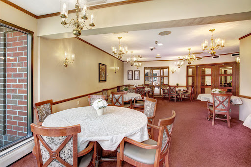 A cozy dining area featuring a round table surrounded by chairs, illuminated by elegant chandeliers.