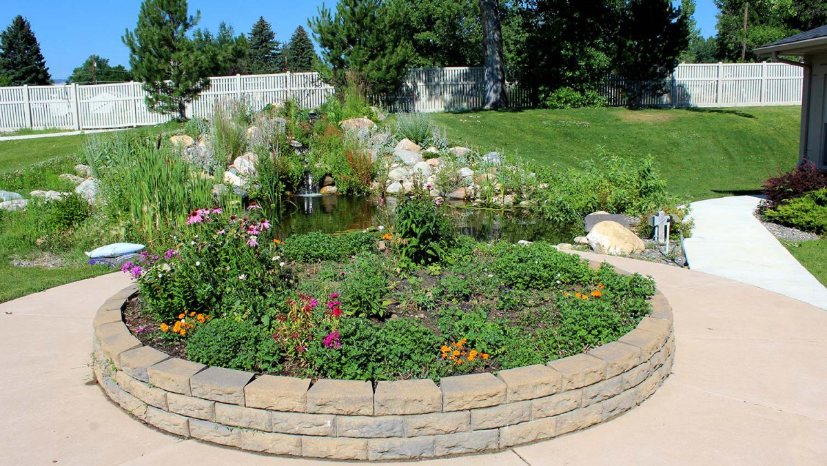 A beautifully landscaped garden with a variety of plants and flowers, featuring a small pond.
