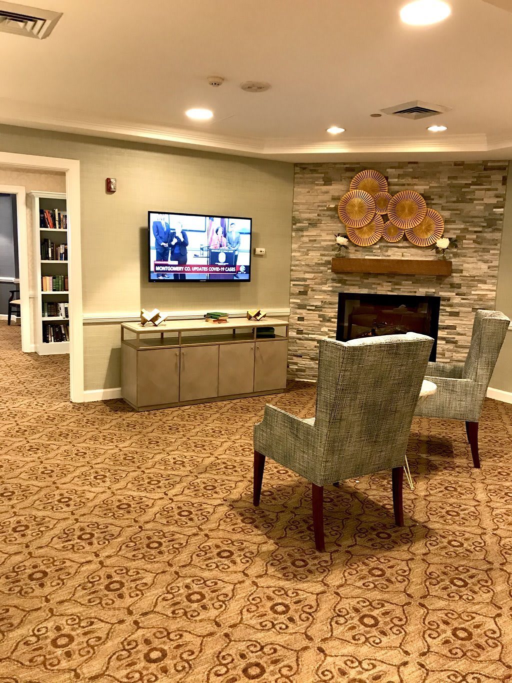 A cozy living room with a television, fireplace, and two armchairs.
