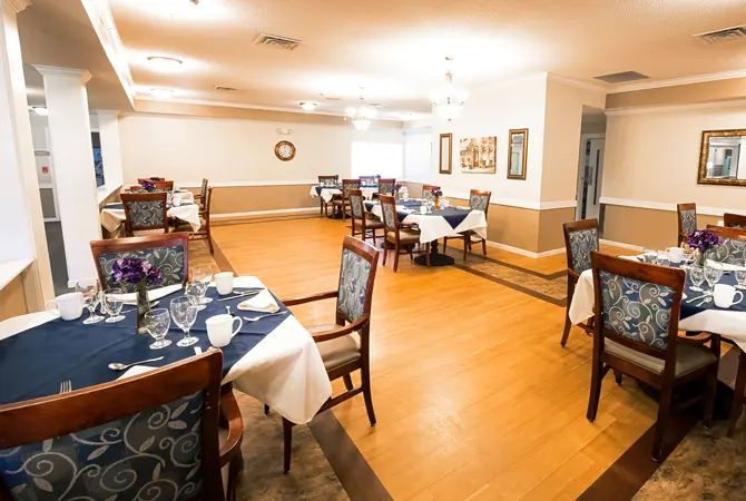 A well-lit dining area with neatly arranged tables and chairs, featuring elegant table settings.