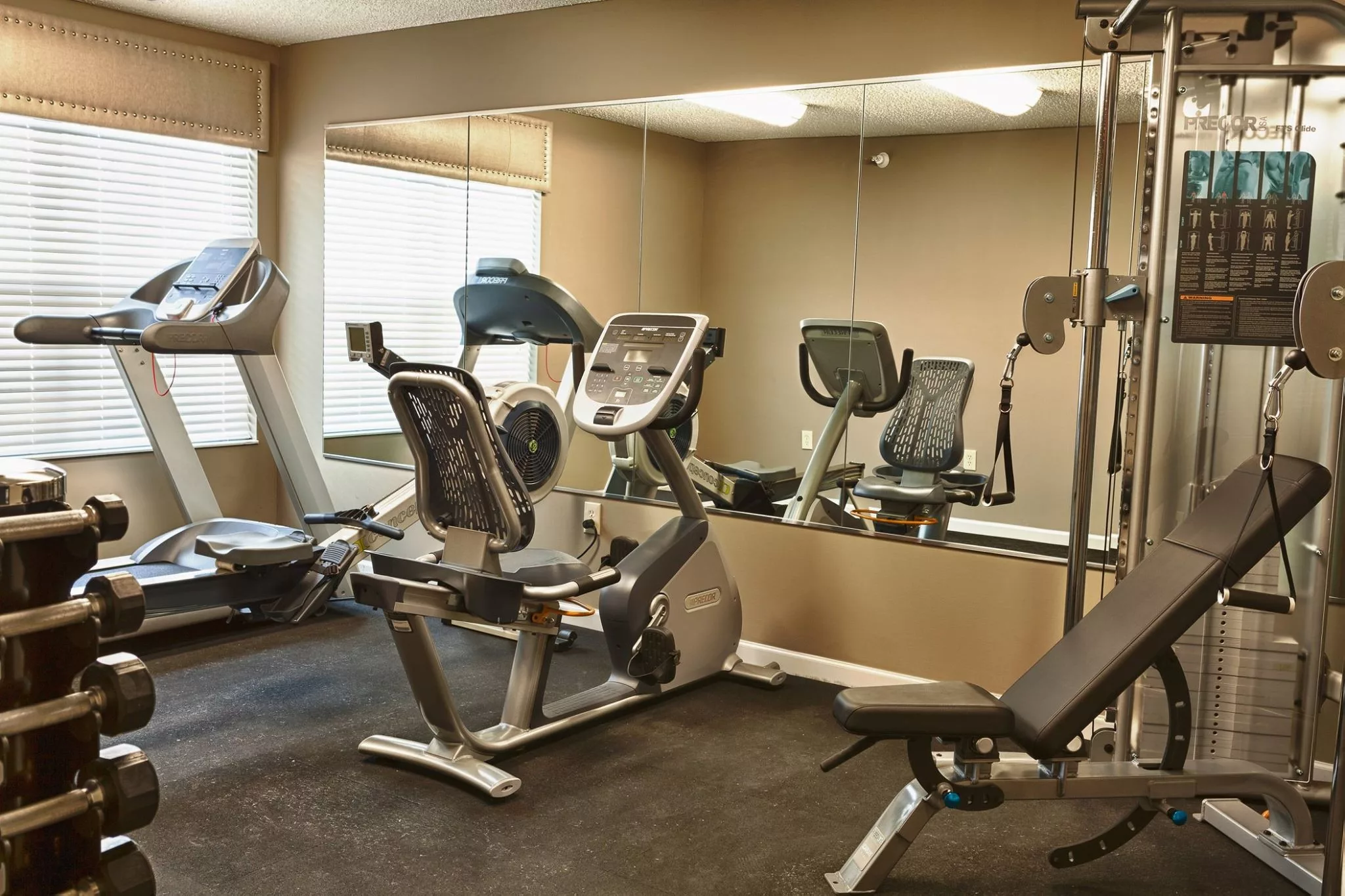 A well-equipped gym with exercise machines including a treadmill and stationary bike.