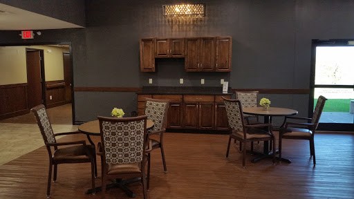 A cozy dining area featuring wooden furniture, a kitchenette, and decorative flowers.