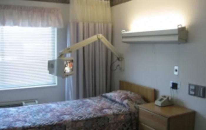 A hospital room with a single patient bed and medical equipment.