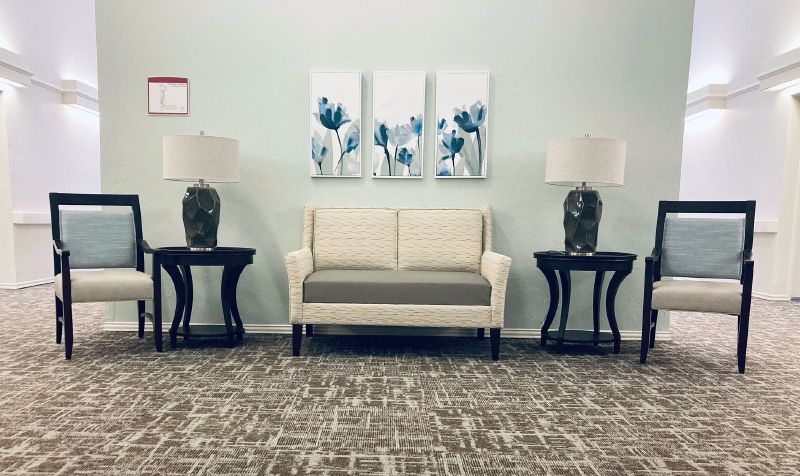 A cozy living room setup featuring a cream sofa, decorative end tables with lamps, and floral artwork on the wall.