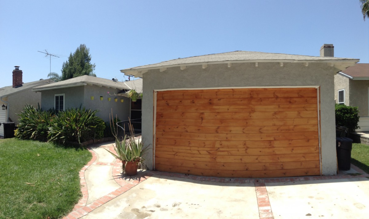 A suburban house with a wooden garage door and driveway.