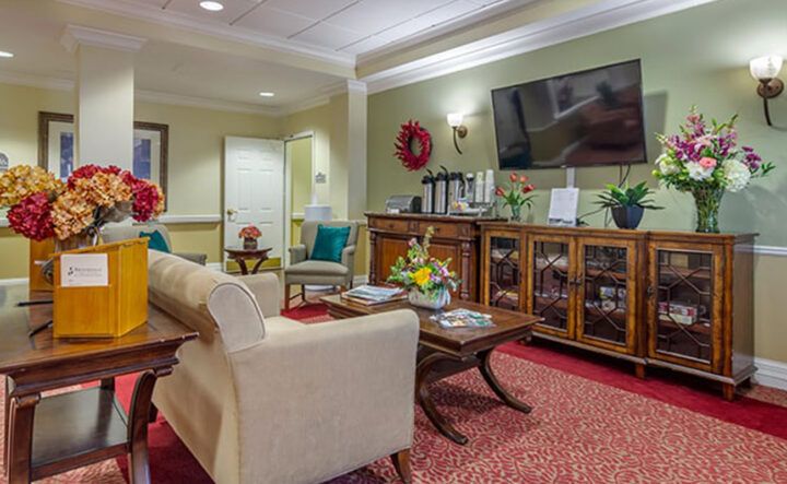 A cozy living room with a sofa, coffee table, and a large TV, decorated with indoor plants and warm lighting.