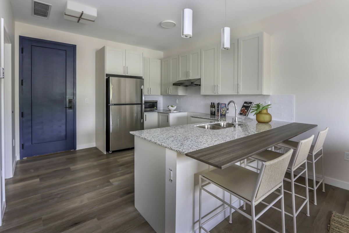 A modern kitchen with white cabinetry, a large island, and stainless steel appliances.
