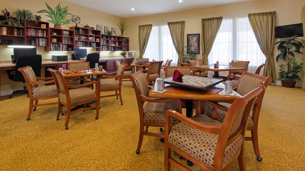 A cozy dining area with wooden tables and chairs, featuring a library-like setting.
