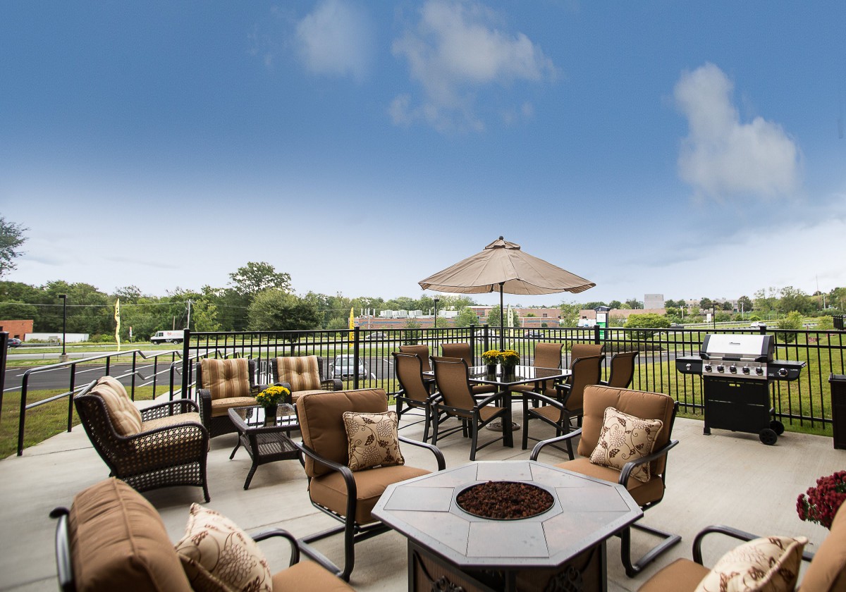 A cozy outdoor patio with comfortable seating, a fire pit, and an umbrella overlooking a scenic landscape.
