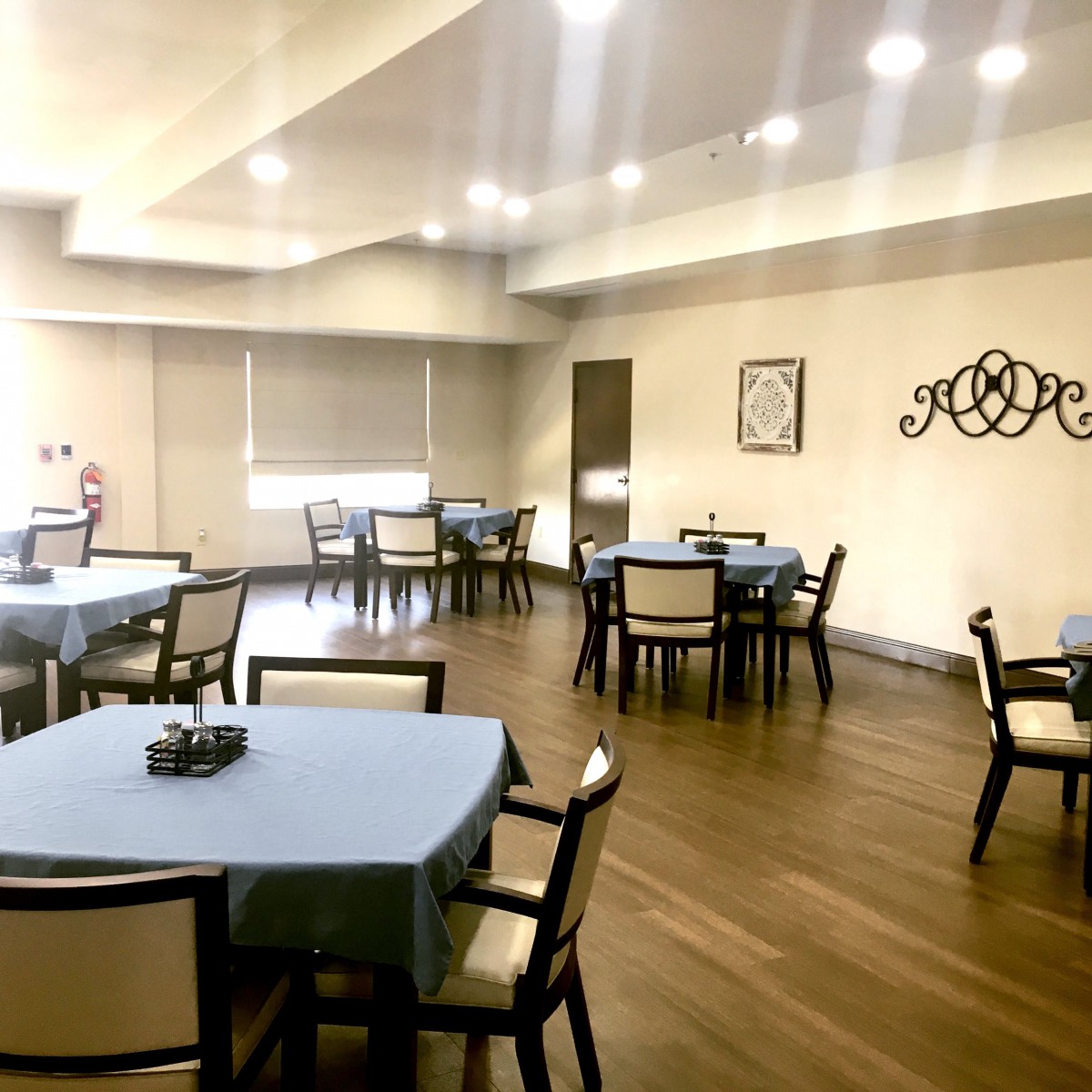 A well-lit dining room with multiple tables and chairs neatly arranged.
