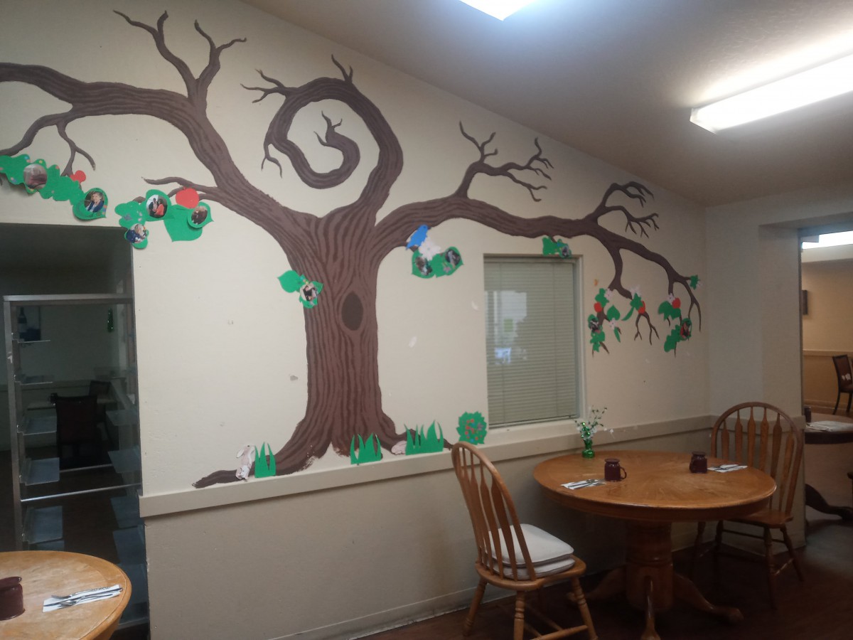 An indoor dining area featuring a mural of a tree with branches extending across the wall.