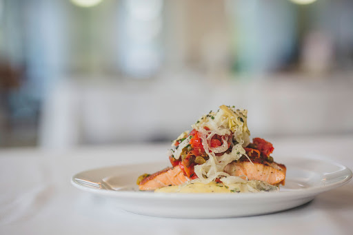 A beautifully plated salmon dish topped with colorful vegetables.