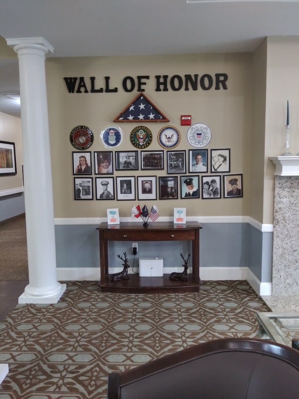 A Wall of Honor displaying military memorabilia and portraits, featuring an American flag in a decorative setting.