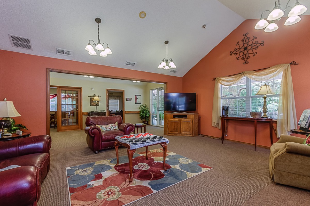 A cozy living room with a sofa, coffee table, TV, and colorful carpet under warm lighting.
