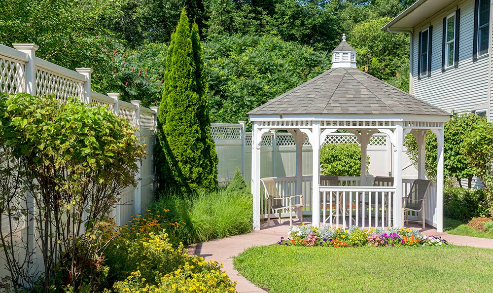 A charming gazebo surrounded by lush greenery and colorful flowers in a serene garden setting.