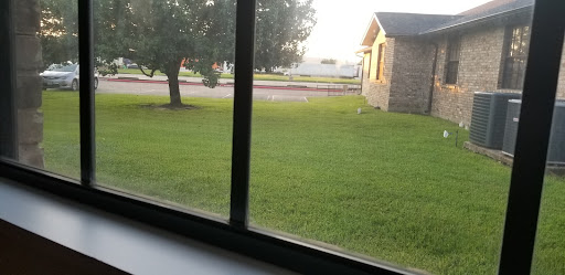 A serene view from a window, showcasing a green lawn and a nearby house.