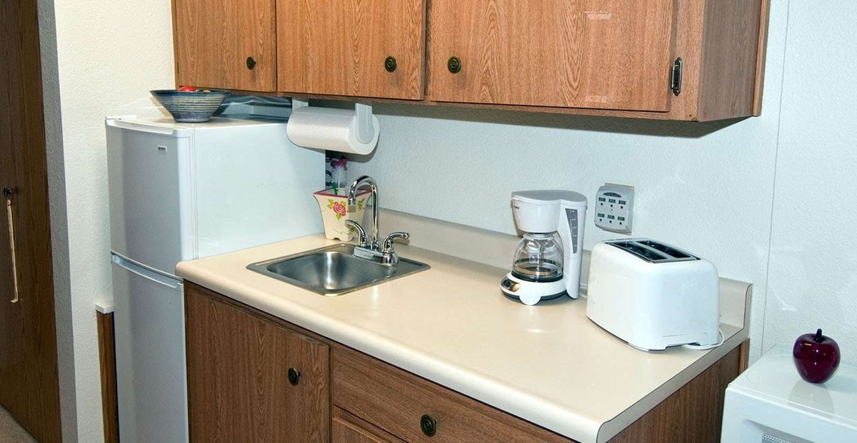 A kitchen with wooden cabinets, featuring a sink, coffee maker, and toaster on the countertop.