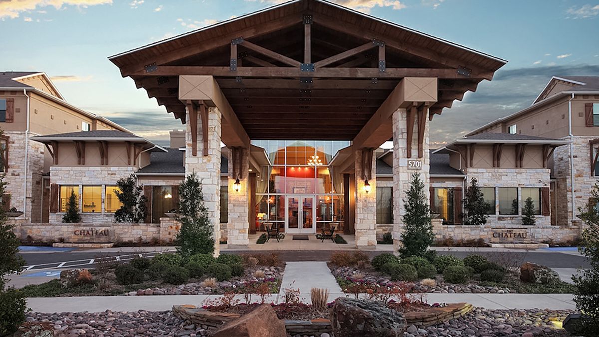 Modern building entrance with stone columns and landscaped surroundings.