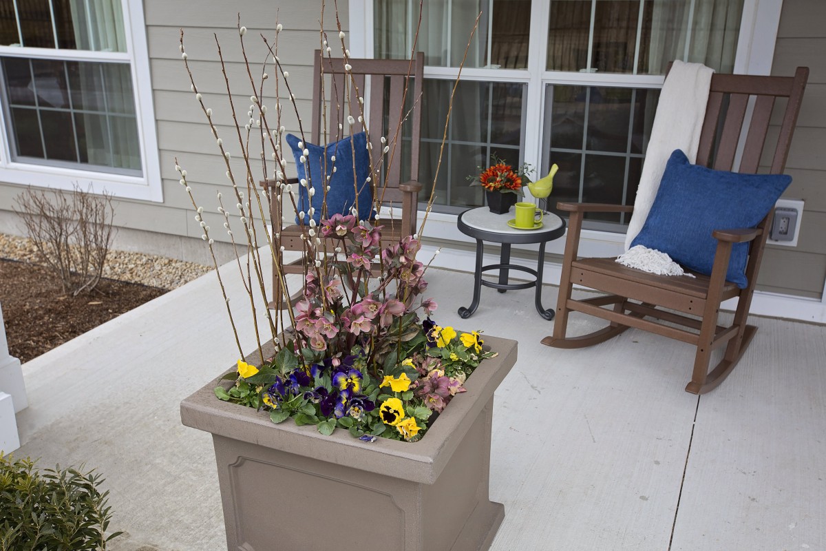 A cozy porch setting with a flower pot arrangement and rocking chairs.