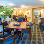 A cozy lounge area with comfortable seating and a table, decorated with plants and warm lighting.